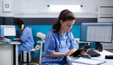 Ein Klinikmitarbeiterin vor einem Tablet