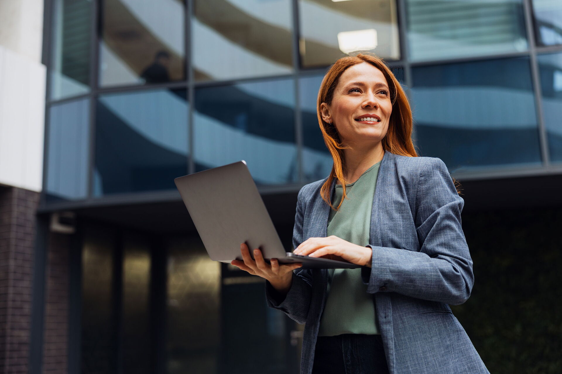 Eine Businessfrau hält ein Laptop in der Hand und ist unterwegs.