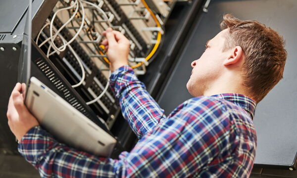 Ein Mann bei der Arbeit am Serverschrank.