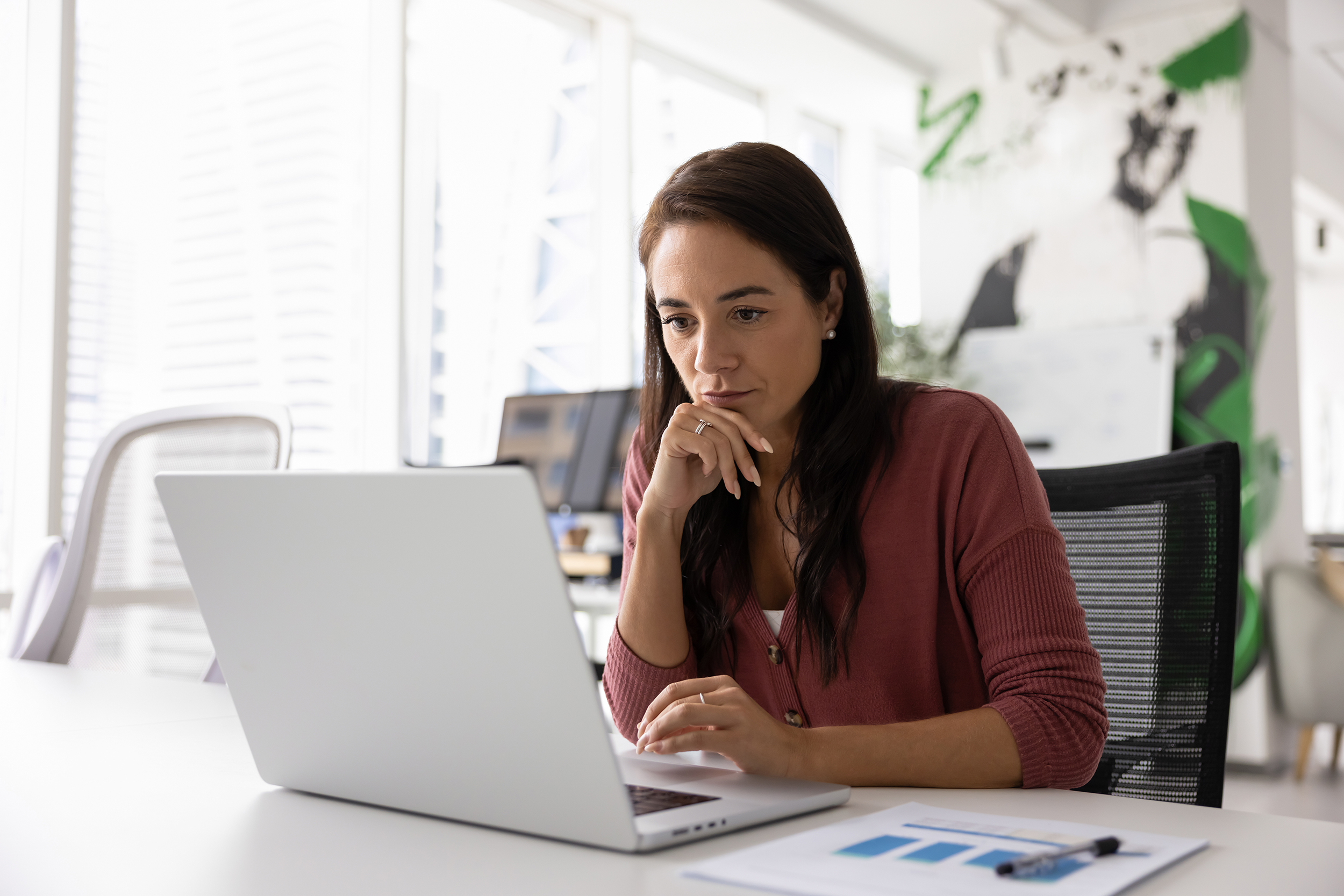 A woman is looking at a laptop.